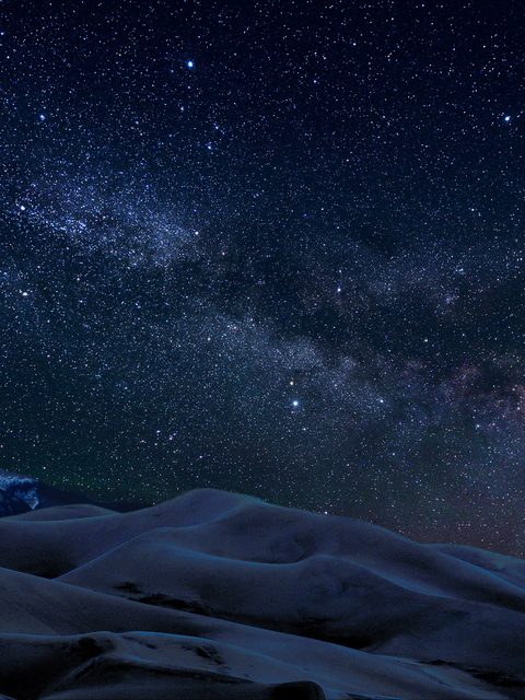 Dark sand dunes under a sky full of stars