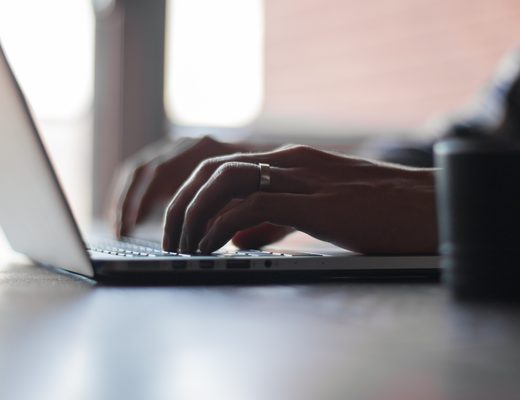 Hands typing on a laptop keyboard in soft light