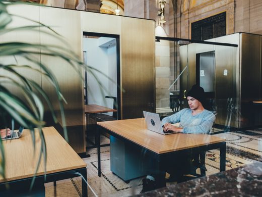 Rows of desks in an open office with glass walls