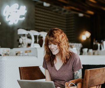 Woman working on a laptop at a cafe table