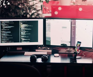 Desk with two screens showing lines of code
