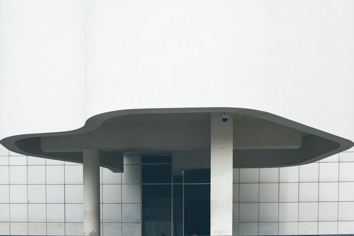 A white modern building with a wide curved concrete canopy over its entrance