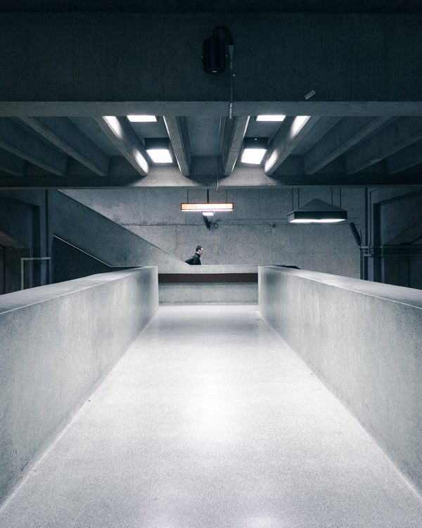 A long grey concrete corridor lit by rows of ceiling lights