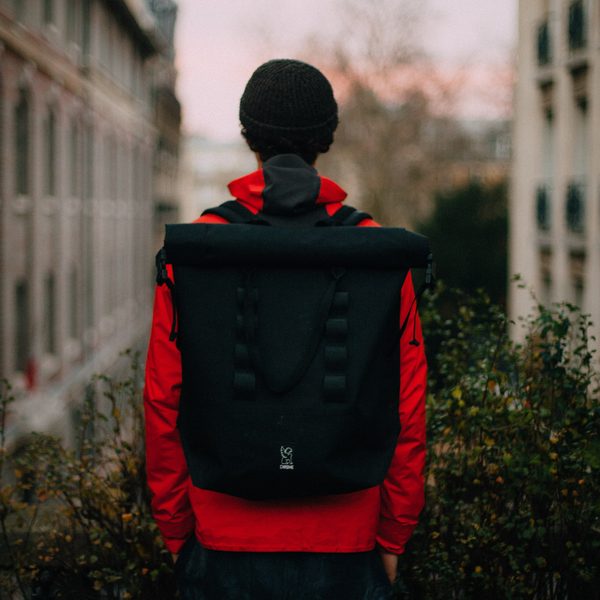 Student from behind wearing a plain black backpack and red jacket
