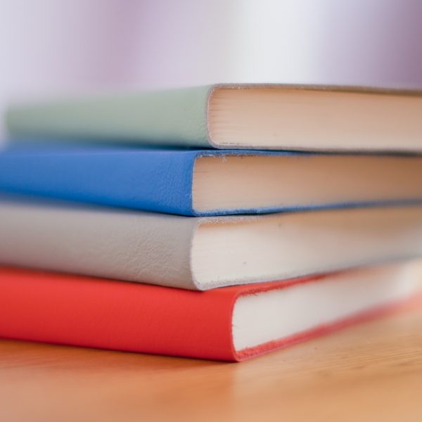 Stack of hardcover notebooks in red, grey, blue and green