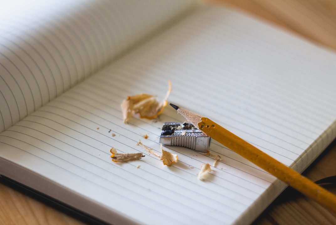 A yellow pencil and fresh shavings on an open lined notebook