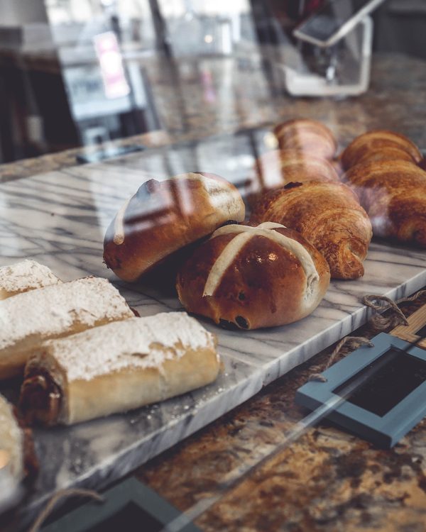 Buns and sugar dusted pastries lined up behind a glass bakery case
