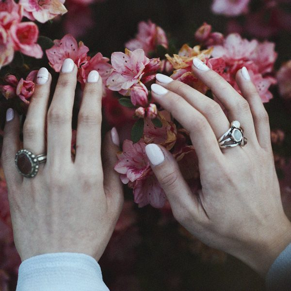 Hands with pearl white nails resting on pink blossoms