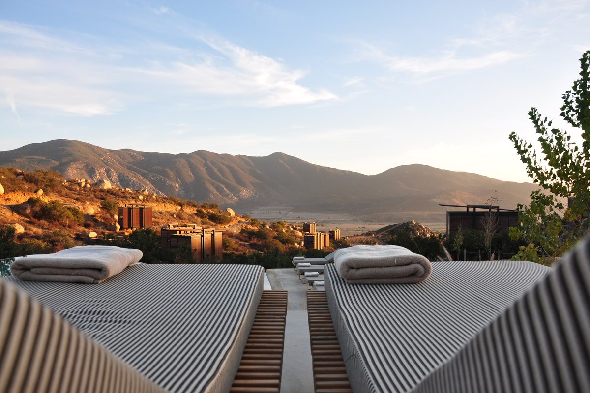 Two loungers with rolled white towels on a sunny terrace facing the hills
