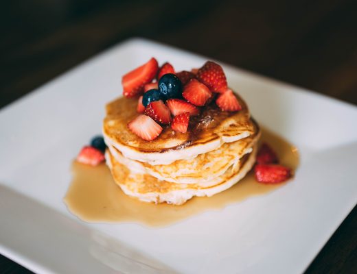 Stack of pancakes with berries and syrup