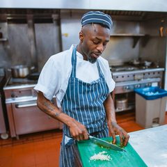 Cook in an apron working at a steel kitchen counter
