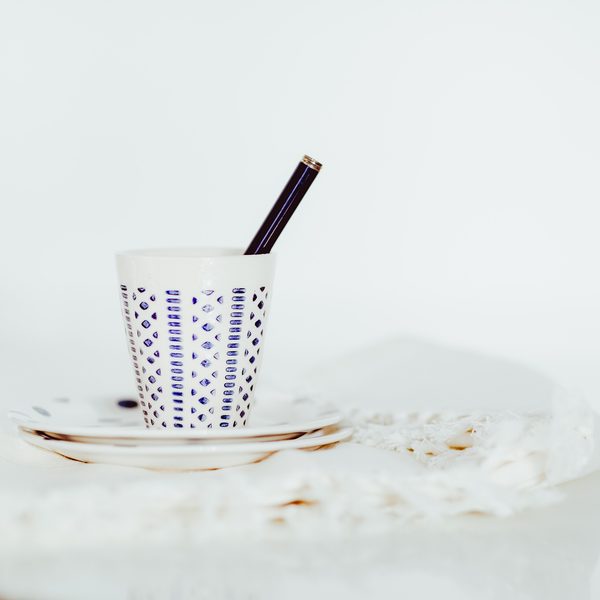 Small patterned porcelain cup on a saucer against a white background
