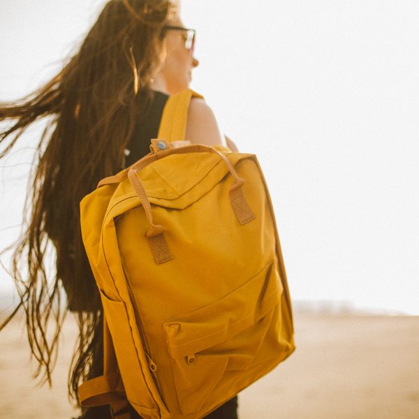 Mustard yellow canvas backpack worn on a windy beach