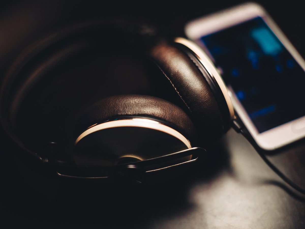 Black over-ear headphones beside a phone on a dark desk