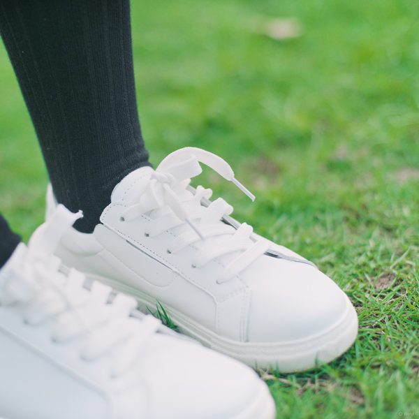 Plain white leather sneakers on green grass