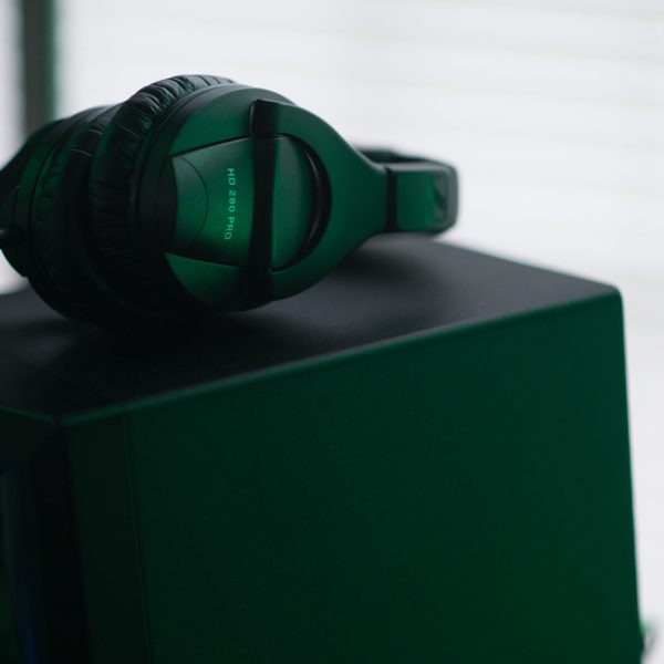 Green over-ear headphones on a dark box under green light