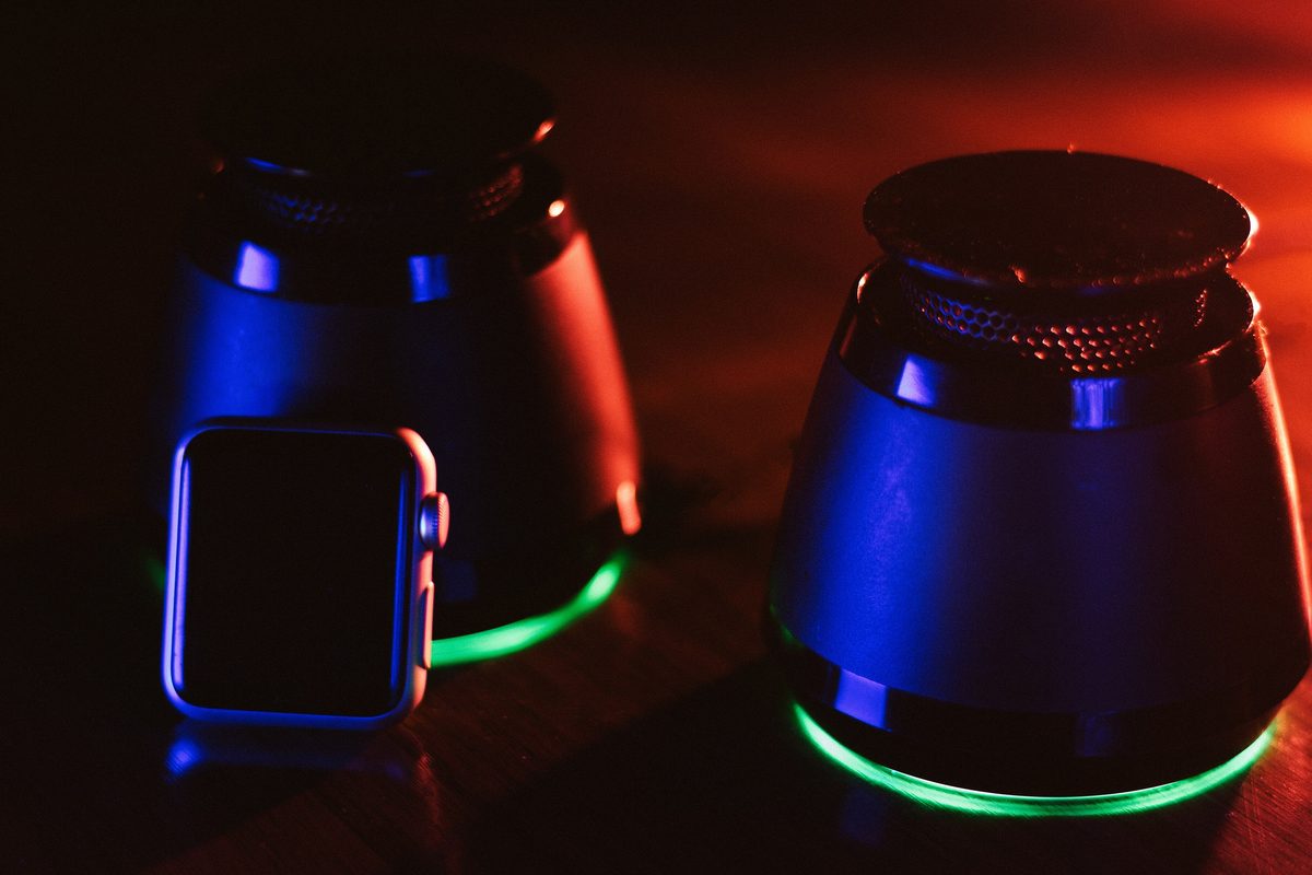 Two small speakers glowing red, blue and green in a dark room