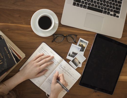 Cup of coffee next to an open paper notebook