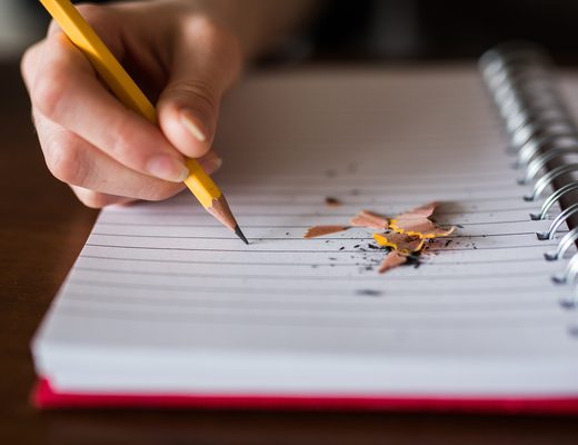 Hand writing in a spiral notebook with a pencil