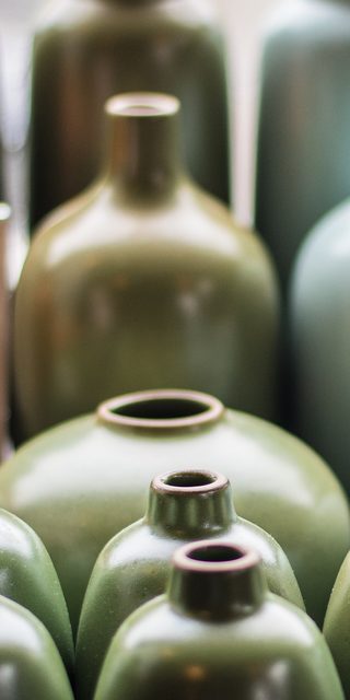 Olive green glazed bottle vases in soft light
