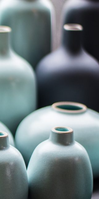 Pale blue and ink black glazed bottle vases in soft light