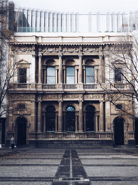 Old stone college building with arched windows on a paved square