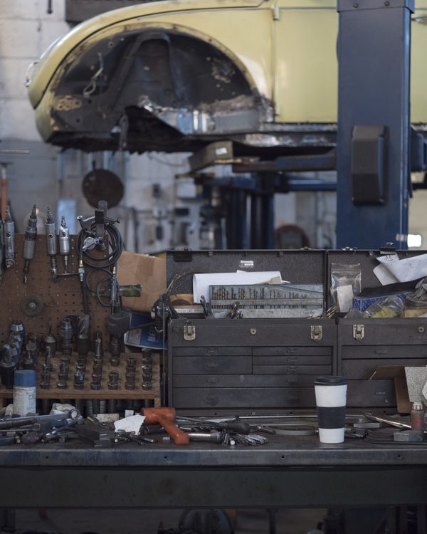 A tidy workbench with tools and shelves below a car on a lift