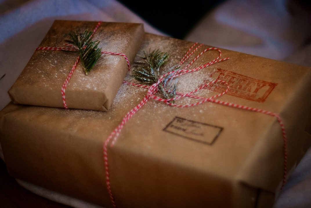 Presents wrapped in kraft paper with red twine and pine sprigs