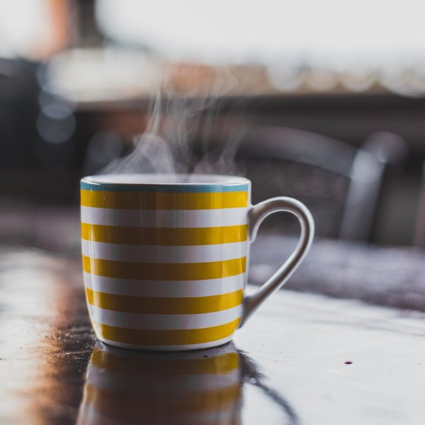 Yellow and white striped mug with steam on a cafe table