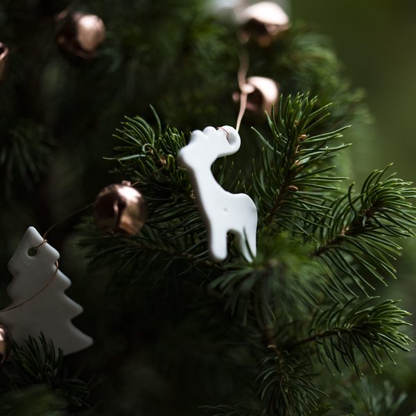 White porcelain reindeer ornament hanging in a fir tree
