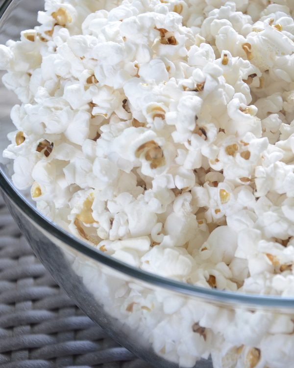 A glass bowl filled to the top with fresh white popcorn