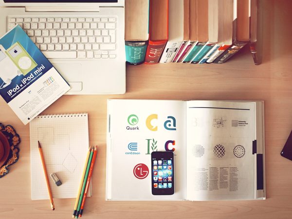 Desk from above with books, pencils, a laptop and a phone