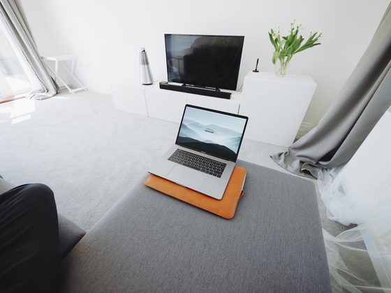 Laptop on a grey sofa in a bright living room