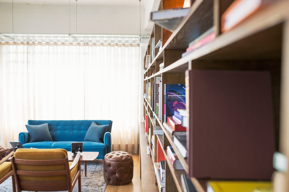 A blue sofa and armchair beside tall shelves full of books in a bright room