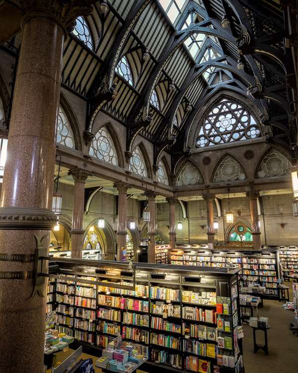 Long rows of bookshelves under the tall arched roof of an old hall