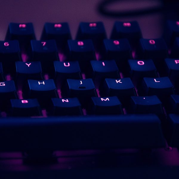 A mechanical keyboard with keys lit in blue and pink light