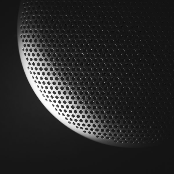 Close up of a round metal speaker grille on a black background