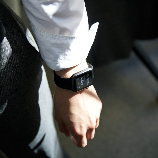 A black smartwatch on the wrist of a man in a white shirt