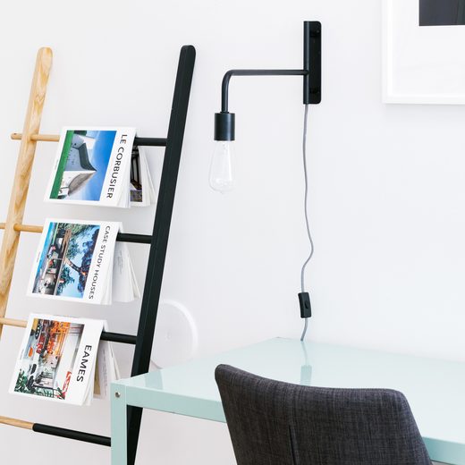 White desk with a wooden ladder shelf holding magazines
