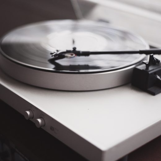Silver turntable with a record on a white shelf