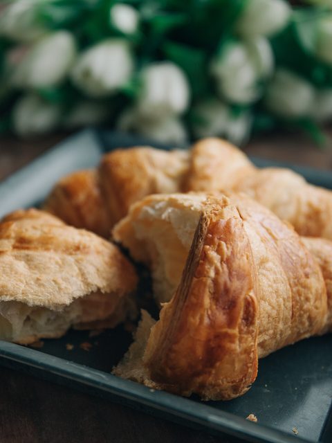 Golden croissants on a dark plate beside a glass of cold brew