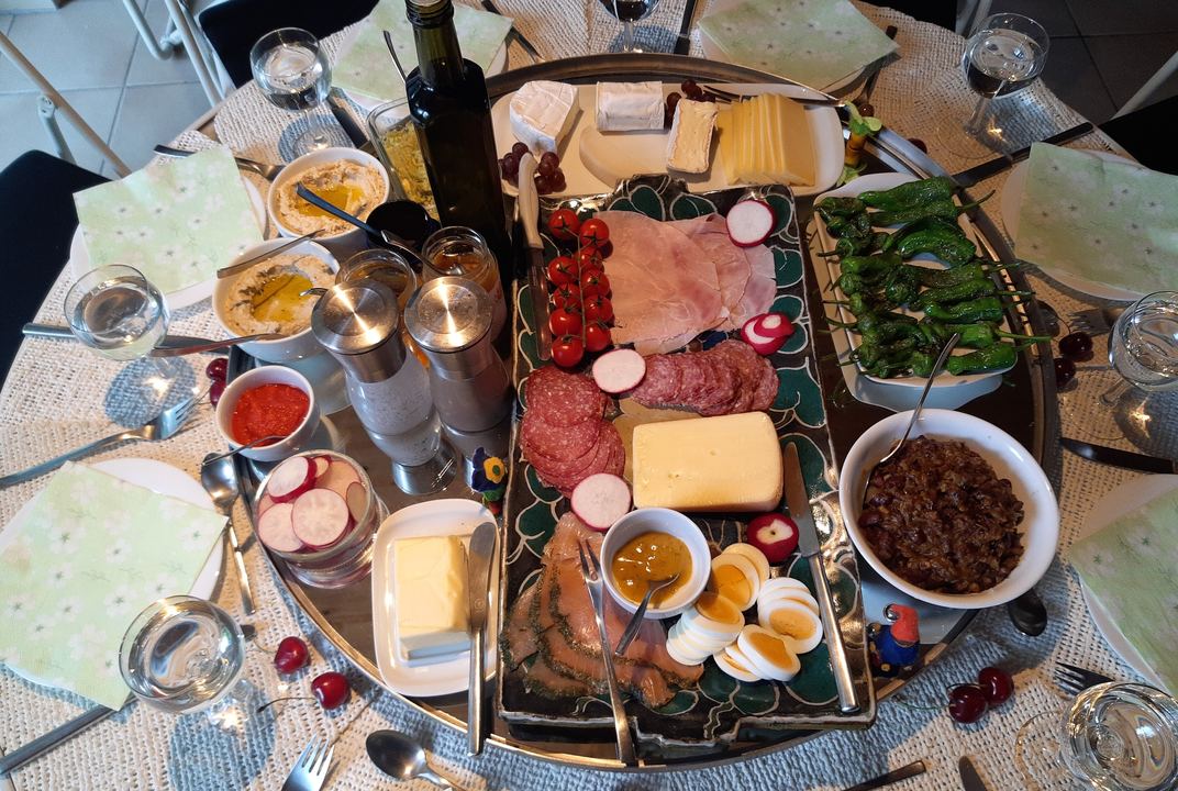A round brunch table set with a platter of cheese, ham, eggs and salads