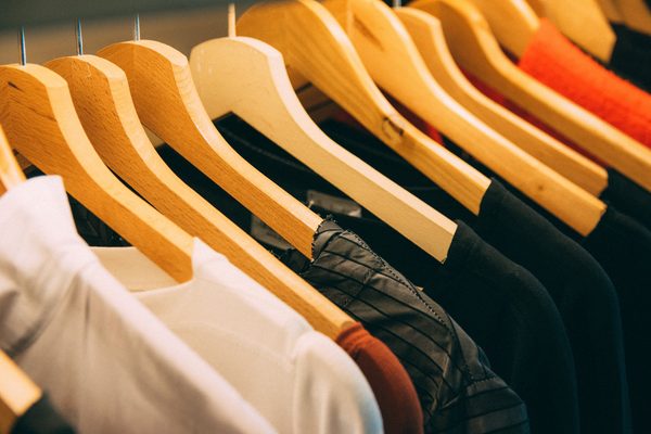 Shirts in white, black and orange on wooden hangers