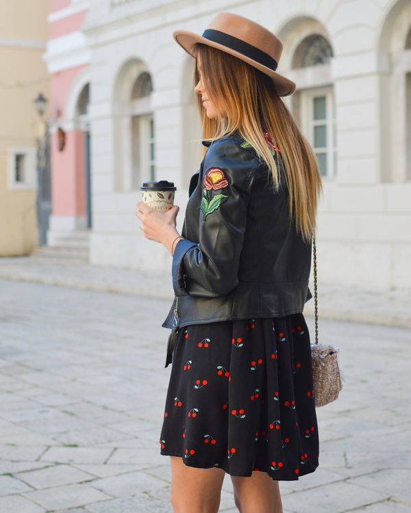 A woman in a straw hat and leather jacket with a small crossbody bag