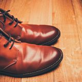 Brown leather lace-up shoes on a wooden floor