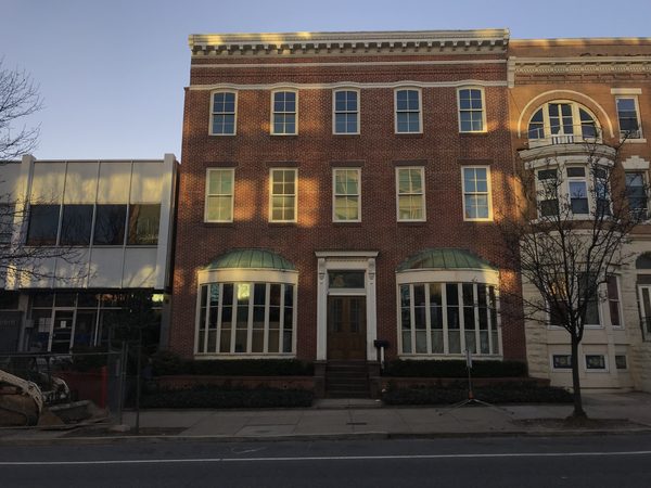 Three story red brick building with arched windows at dusk