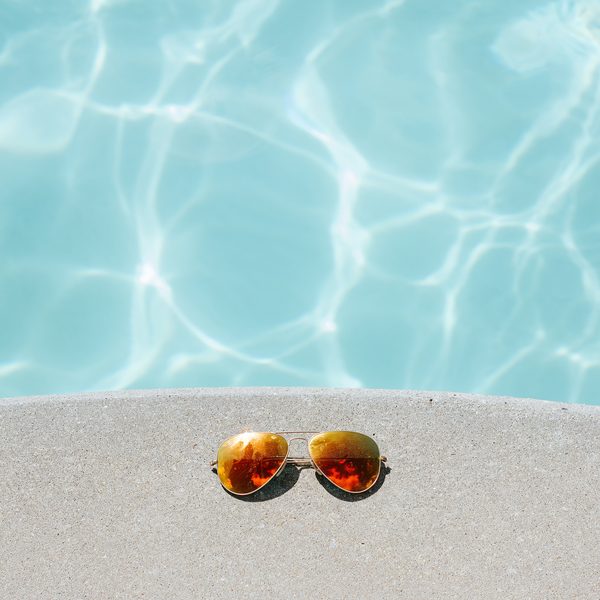 Gold aviator sunglasses resting on the edge of a pool