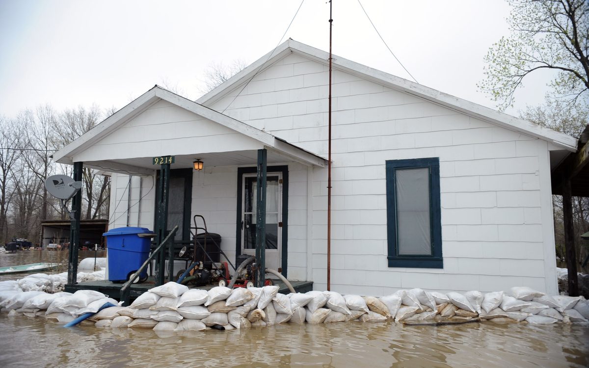 White house ringed with sandbags, with flood water up to the bags