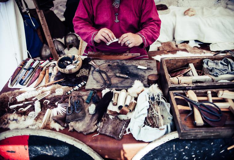 Hands at work over a bench of leather pieces and hand tools