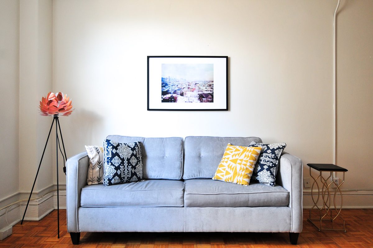 Light blue sofa with patterned cushions and a floor lamp in a bright room